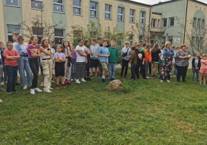 Grupa uczniów stoi przed budynkiem szkoły