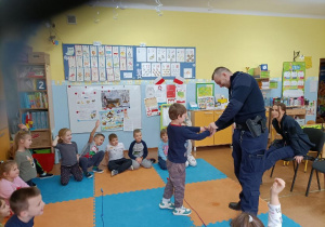 Uczeń stoi przed policjantem który przymierza mu kajdanki