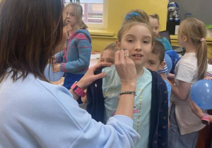 Pani pedagog maluje serduszko na policzku uczennicy
