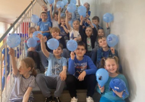 Uczniowie siedzą na schodach z balonami