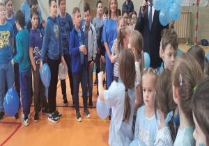 Uczniowie stoją na hali gimnastycznej i słuchają wypowiedzi Pana Prezydenta