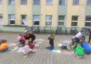 Uczniowie malują kolorową kredą