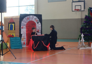Dwóch uczniów w czarnych strojach wygłasza kwestie