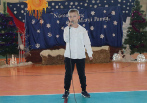 Uczeń w stroju galowym śpiewa kolęde