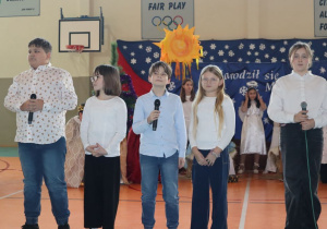 Uczniowie w strojach galowych śpiewaja