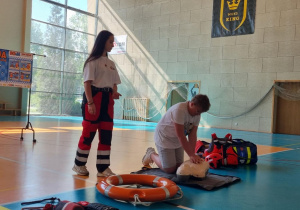 Uczeń udziela pierwszej pomocy obok stoi ratowniczka