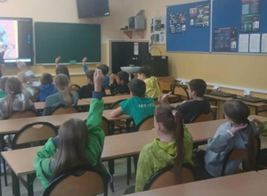 Uczniowie siedzą w ławkach i słuchają wykładu