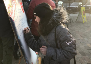 Uczennica podpisuje się na tablicy Wielkiej Orkiestry Świątecznej Pomocy.