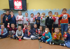 Uczniowie kl. 0 trzymją własnoręcznie wykonane pacynki w barwach narodowych.