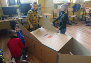 Czterech uczniów robi rakietę z kartonu.