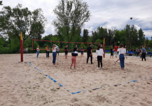 Uczniowie grają w siatkówkę plażową na przystani.