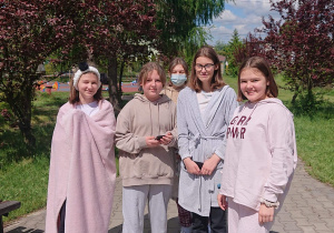 Uczniowie stoją w pidżamach szlafrokach na wybiegu szkolnym.