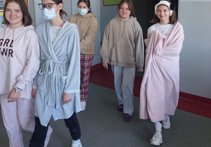 Pięcioro uczniów przechodzi korytarzem szkolnym w pidżamach szlafrokach.
