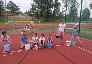 Uczniowie na boisku szkolnym przygotowują się do bitwy na gąbki.