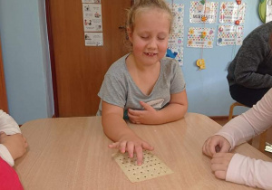 Uczennica odczytuje napis alfabetem Braille'a.