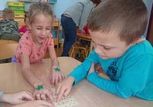 Dwoje uczniów odczytuje napis alfabetem Braille'a.