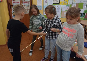 Czworo uczniów ogląda laskę dla niewidomych.