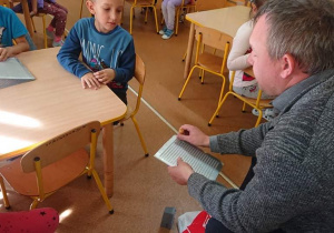 Mężczyzna odczytuje napis alfabetem Braille'a.