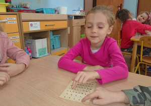 Uczennica odczytuje napis alfabetem Braille'a.