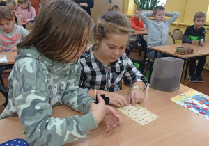 Dwie uczennice odczytują napis alfabetem Braille'a.