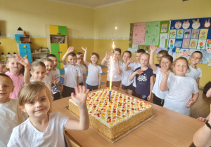 Uczniowie pozują do zdjęcia z tortem.