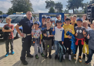 Uczniowie pozują do zdjęcia z policjantem.