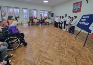 Występ grupy młodzieży, obok seniorzy z Domu Pomocy Społecznej