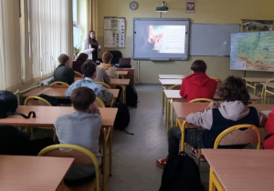 Uczniowie siedzą w ławkach i aktywnie uczestniczą w dyskusji