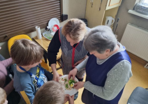 Dzieci częstują pracowników szkoły kanapkami.