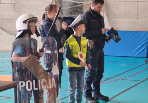 Dwóch uczniów ubranych w mundury policjantów stoją obok policjantów