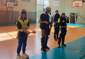 Dwoje uczniów ubranych w mundury policjantów stoją obok policjantów