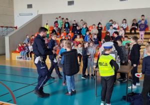 Uczeń w stroju policjanta stoi wśród dzieci