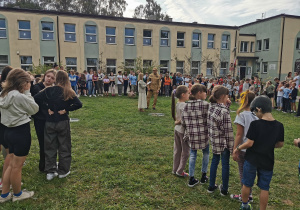 Grupa uczniów stoi przed budynkiem szkoły