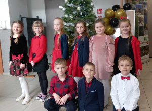 Grupa dzieci pozuje do zdjęcia na tle choinki