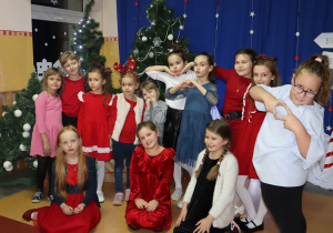 Grupa dziewcząt pozuje do zdjęcia na tle choinek