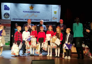 Grupa uczniów stoi na scenie i cieszą się z nagrody