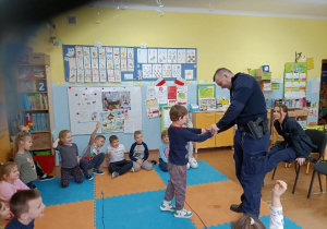 Uczeń stoi przed policjantem który przymierza mu kajdanki