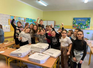 Grupa dzieci pozuje do zdjęcia na tle pizzy