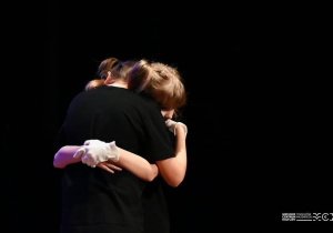 Dwie postacie na scenie przytulają się