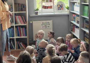 Pani bibliotekarka opowiada dzieciom o książkach a dzieci siedzą na dywanie