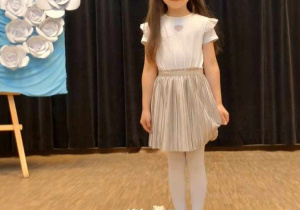 Natalia stoi na scenie za koszem z kwiatami
