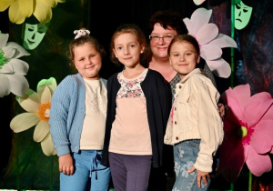 Trzy uczennice z wychowawczynią pozują na scenie