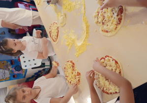 Uczniowie dekorują pizzę