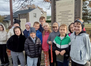 Uczniowie stoją przed pamiątkową tablicą