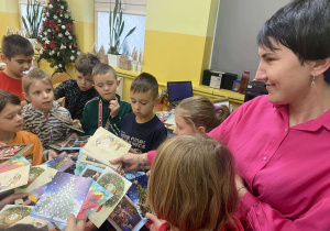 Nauczyciel odbiera od dzieci pocztówki świąteczne.