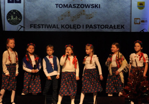 Grupa dzieci śpiewa na scenie