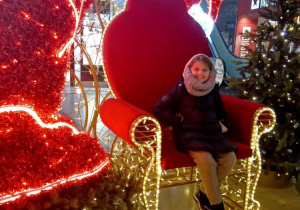 Dziewczynka siedzi na fotelu i pozuje do zdjęcia