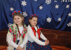 Dwie dziewczynki siedzą na tle dekoracji