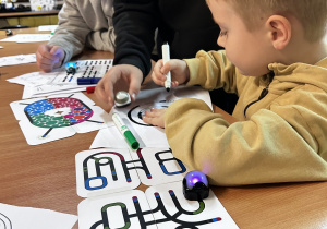 Trzech uczniów siedzi przy stoliku