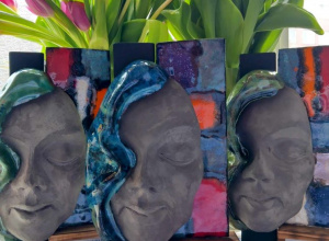 Statuetki trzech masek na tle tulipanów